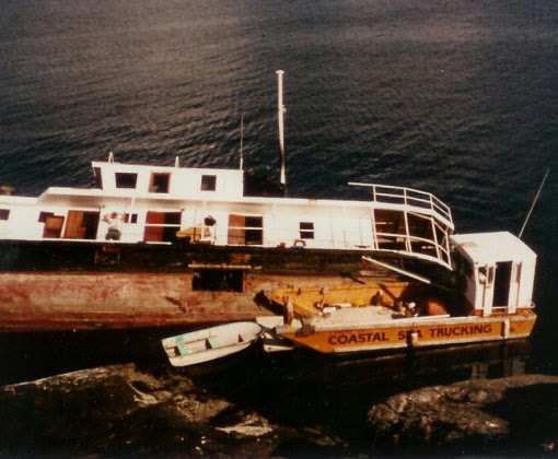 Bill's first boat, the Sealander 59, a 27-foot fibreglass landing craft lettered Coastal Sea Trucking, tied up at the shore beside a larger hull