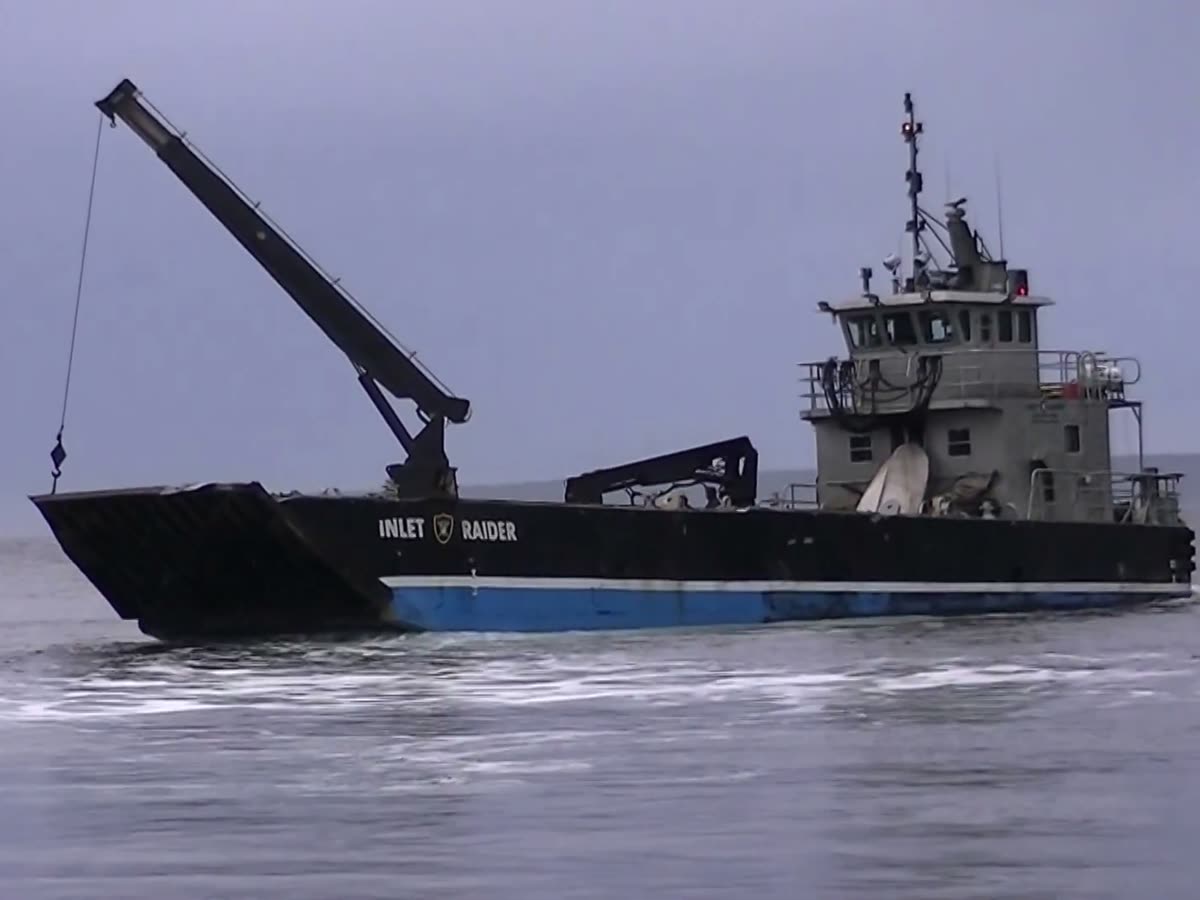 The Inlet Raider on a grey day, black hull with her name and shield, crane raised