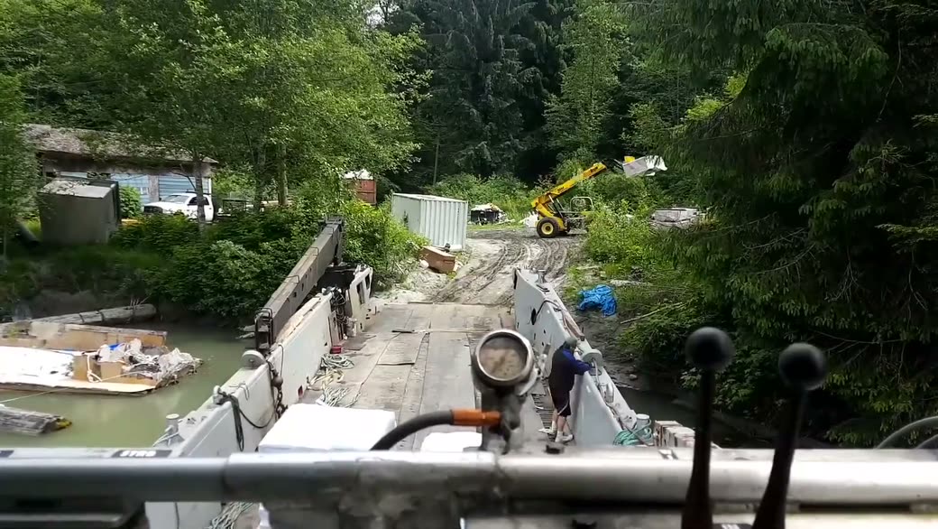 The bow ramp down on a muddy bank, a telehandler working on the site behind